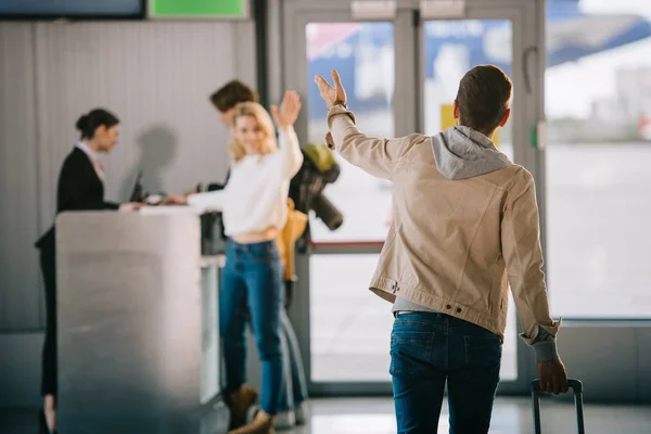 Jóvenes amigos saludando las manos en el mostrador de facturación en el aeropuerto — Stock Photo