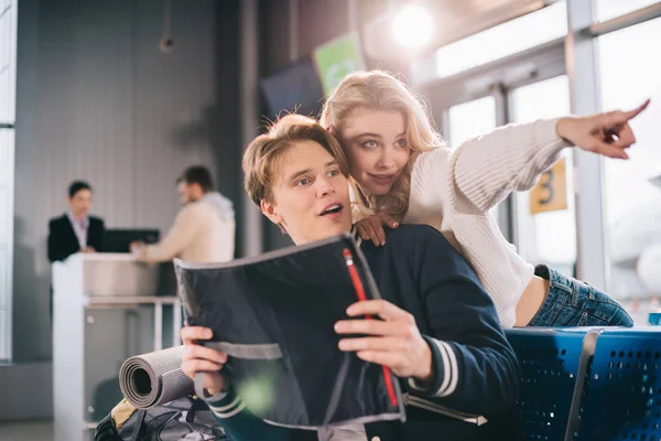 Junges Paar blickt auf Landkarte und schaut im Flughafen weg — Stockfoto