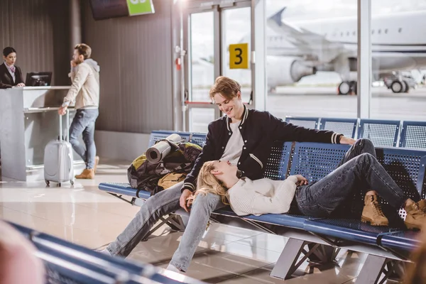 Young couple smiling each other while waiting for flight in airport — Stock Photo