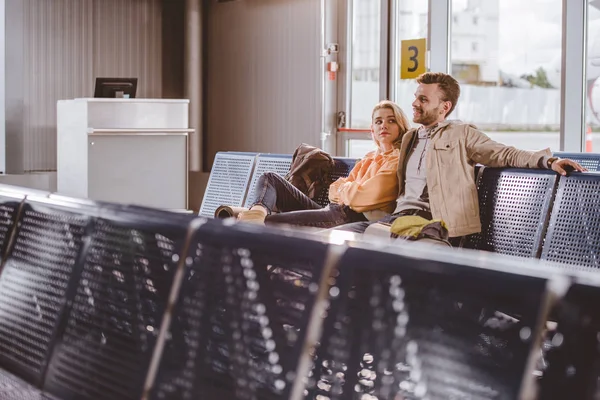Focus selettivo di giovani coppie sedute insieme e in attesa di volo in aeroporto — Foto stock
