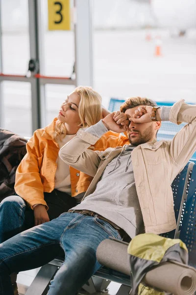 Gelangweiltes junges Paar sitzt zusammen und wartet auf Flug am Flughafen — Stockfoto