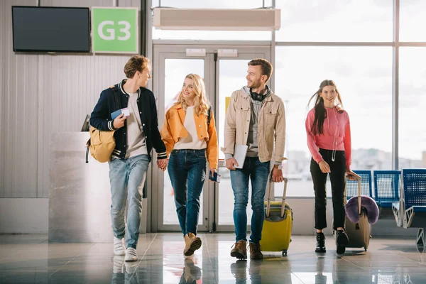 Giovani amici sorridenti con zaini e valigie nel terminal dell'aeroporto — Foto stock