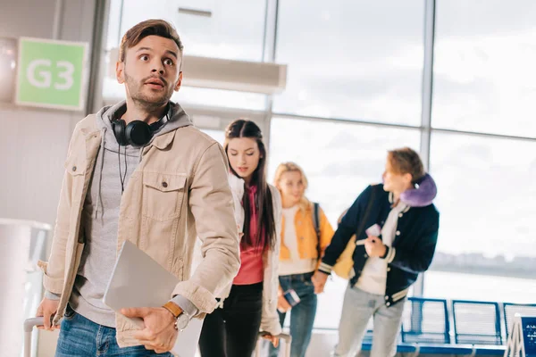 Group of young friends with luggage in airport terminal — Stock Photo