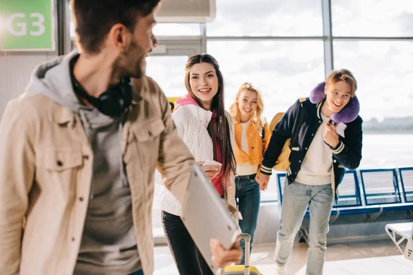 Усміхнені молоді люди поспішають до польоту в аеропорту — стокове фото