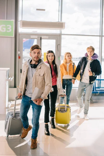 Jóvenes con maletas en la terminal aeroportuaria - foto de stock