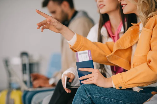 Ritagliato colpo di ragazza in possesso di passaporto con carta d'imbarco e puntando con il dito in aeroporto — Foto stock