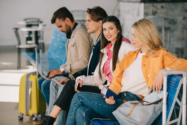 Jeunes assis ensemble et en attente de vol dans le terminal de l'aéroport — Photo de stock