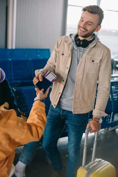Cropped shot of friends holding passport with boarding passes while waiting in airport — Stock Photo