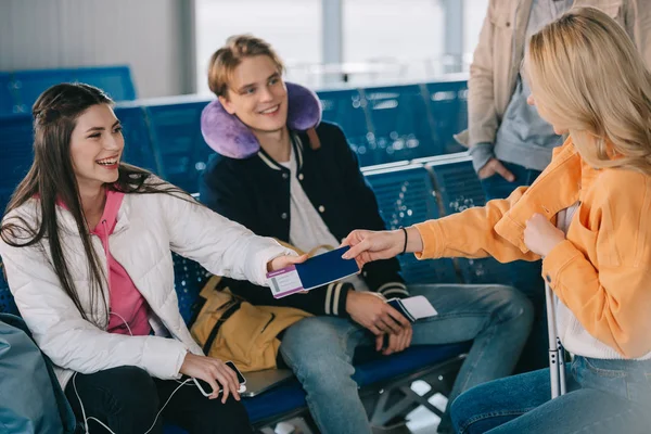 Amigos con pasaporte con tarjeta de embarque mientras esperan en la terminal del aeropuerto - foto de stock