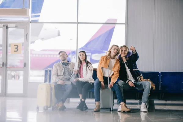 Young friends with luggage waiting in airport terminal — Stock Photo