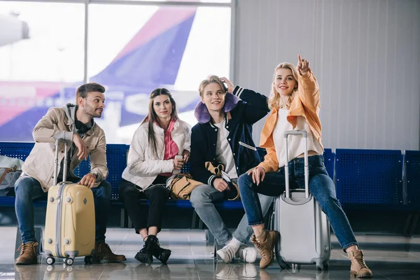 Jóvenes viajeros hablando mientras esperan en la terminal del aeropuerto - foto de stock