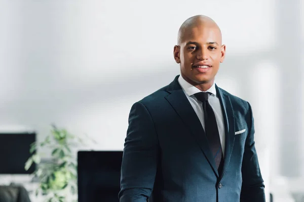 Retrato de belo jovem empresário afro-americano sorrindo para a câmera no escritório — Fotografia de Stock