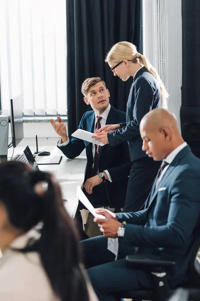 Jóvenes colegas de negocios multiétnicos que trabajan con dispositivos digitales en oficinas de espacio abierto - foto de stock