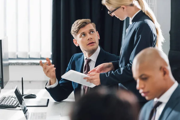 Junge Geschäftskollegen nutzen digitale Geräte und diskutieren über Projekte im Büro — Stockfoto