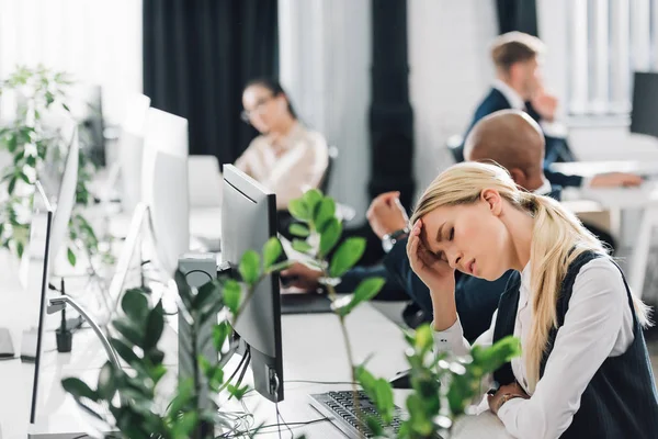 Sick young woman suffering from headache at workplace — Stock Photo