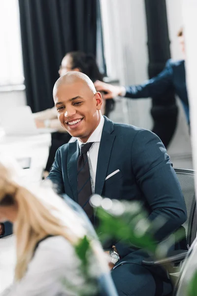 Feliz joven afroamericano hombre de negocios riendo en el lugar de trabajo - foto de stock