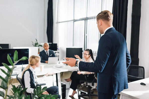 Jungunternehmer gestikuliert und spricht mit Kollegen im Großraumbüro — Stockfoto