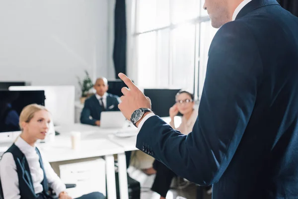 Cropped shot of young businessman gesturing and talking with colleagues in open space office — Stock Photo
