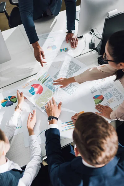 Recortado disparo de joven equipo de negocios trabajando con gráficos y gráficos en la oficina - foto de stock