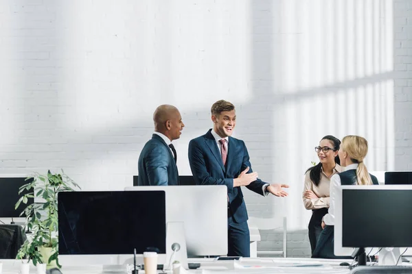 Emotional young businessman talking with colleagues at workplace — Stock Photo