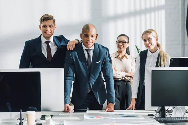 Professionelle junge multiethnische Geschäftsleute stehen zusammen und lächeln in die Kamera im Büro — Stockfoto