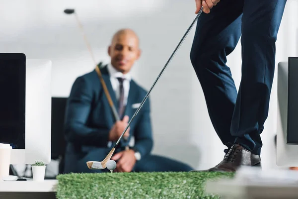 Low section of young businessman playing golf in office — Stock Photo