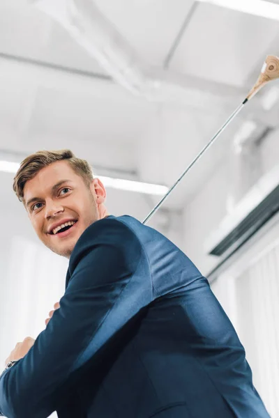 Blick auf einen glücklichen jungen Geschäftsmann, der im Großraumbüro Golf spielt — Stockfoto