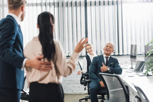 Homme d'affaires présentant un nouveau collègue agitant la main et saluant ses collègues au bureau — Photo de stock