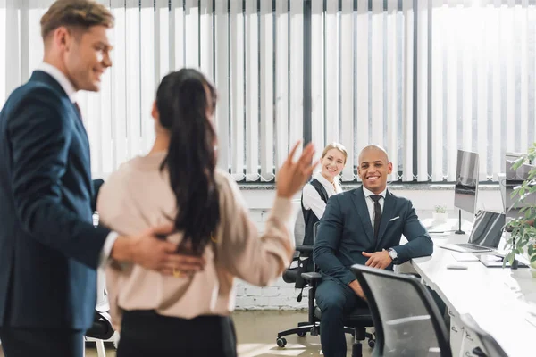 Lächelnder Geschäftsmann blickt auf neuen Kollegen, winkt und grüßt Kollegen im Büro — Stockfoto