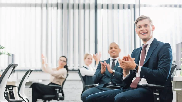 Felices jóvenes colegas de negocios multiétnicos aplaudiendo en el cargo - foto de stock