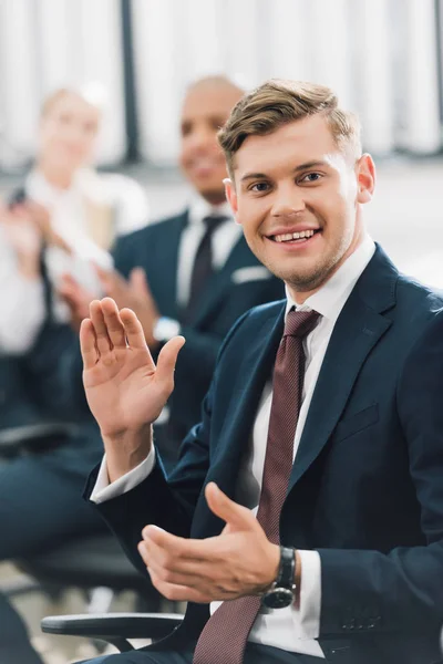 Jovem empresário feliz acenando a mão e sorrindo para a câmera no escritório — Fotografia de Stock