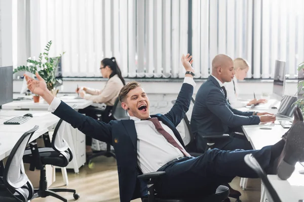 Eccitato giovane uomo d'affari trionfante mentre lavora in ufficio — Foto stock