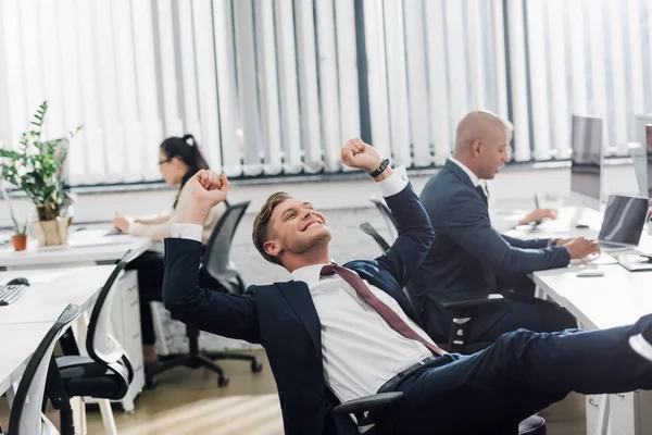 Felice giovane uomo d'affari trionfante mentre lavora con i colleghi in ufficio open space — Foto stock