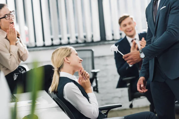 Cropped shot of businessman presenting origami flower to happy businesswoman in office — Stock Photo