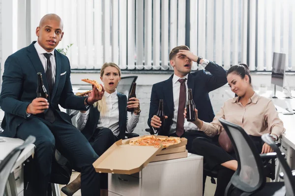 Emotivo giovani uomini d'affari bere birra e mangiare pizza in ufficio — Foto stock