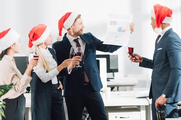 Щасливі молоді багаторасові ділові люди в капелюхах Санти святкують Різдво в офісі — стокове фото