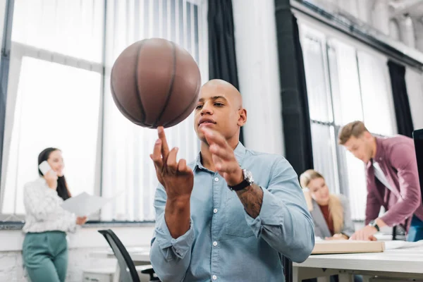 Baixo ângulo de visão do jovem afro-americano jogando com bola de basquete no escritório — Fotografia de Stock
