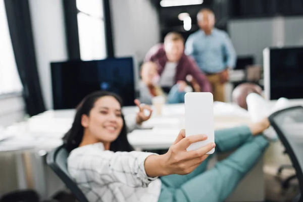 Happy young businesswoman taking selfie with smartphone in open space office — Stock Photo