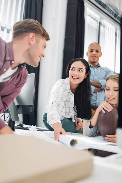 Glückliche junge Geschäftsleute lächeln, während sie gemeinsam im Großraumbüro arbeiten — Stockfoto