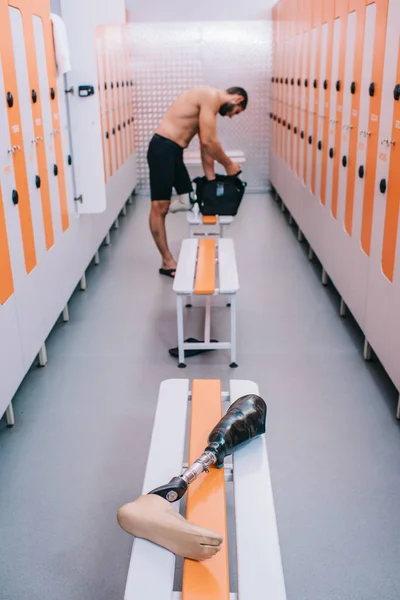 Young sportsman with artificial leg at changing room of gym — Stock Photo