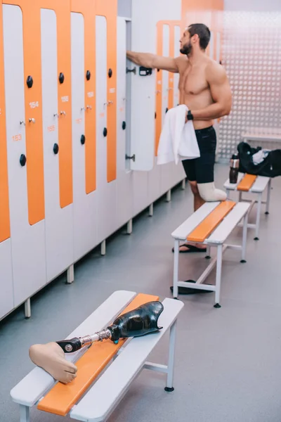 Athletic young sportsman with artificial leg at changing room of swimming pool — Stock Photo