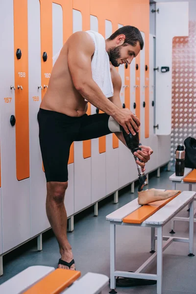Улыбающийся молодой спортсмен с искусственной ногой стоит у раздевалки бассейна — стоковое фото