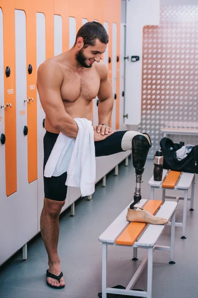 Glücklicher junger Sportler mit Beinprothese steht in der Umkleidekabine des Schwimmbades — Stockfoto