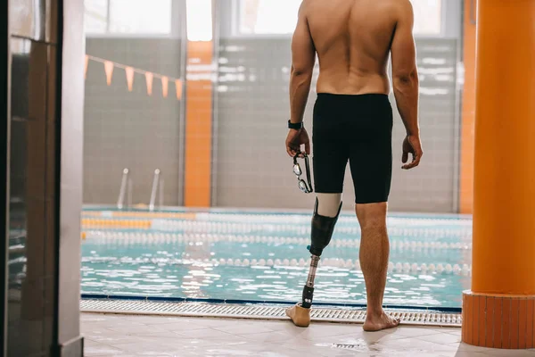 Tiro recortado de desportista com perna artificial em pé na frente da piscina interior — Fotografia de Stock