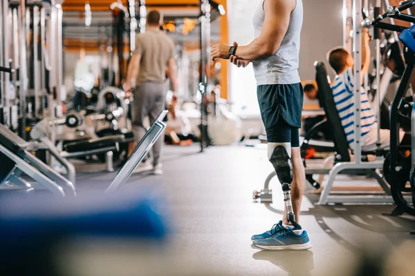 Plan recadré de jeune sportif avec jambe artificielle debout à la salle de gym — Photo de stock