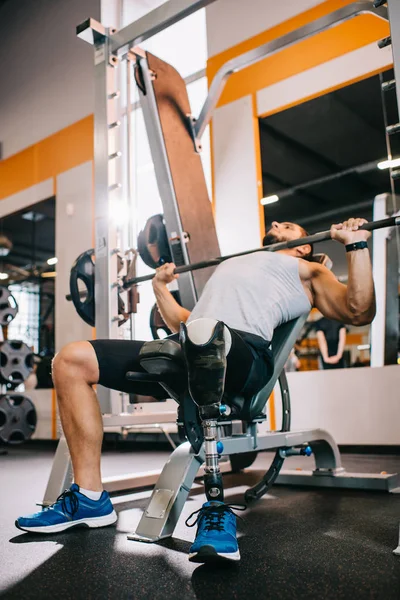 Caber jovem desportista com perna artificial levantar barbell no ginásio — Fotografia de Stock