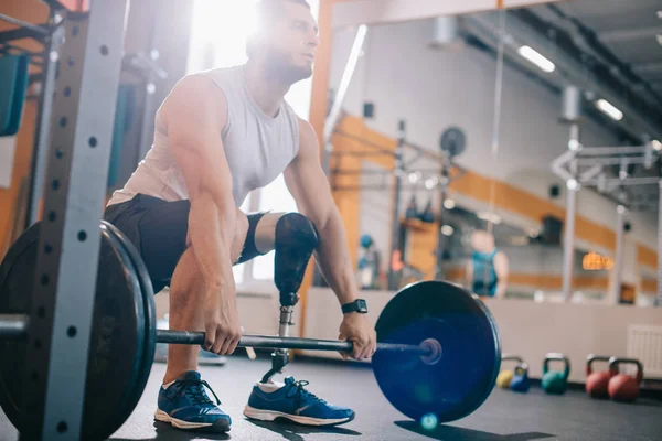 Jovem desportista atraente com perna artificial trabalhando com barbell no ginásio — Fotografia de Stock