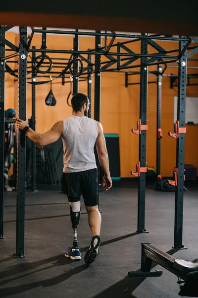 Красивий молодий спортсмен зі штучною ногою спирається на гімнастичні сходи в спортзалі — стокове фото