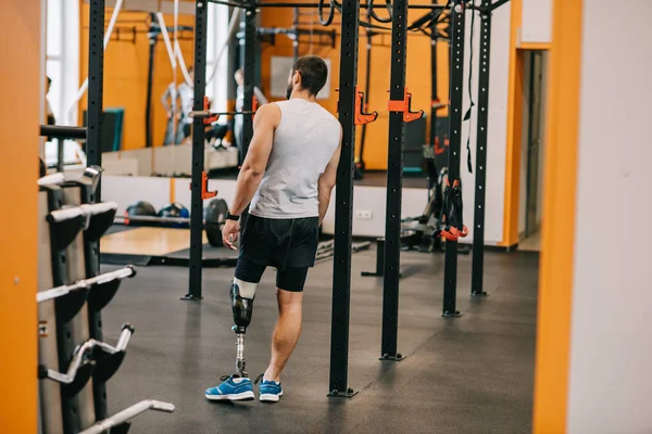 Красивий молодий спортсмен зі штучною ногою, що стоїть біля гімнастичної драбини в спортзалі — стокове фото