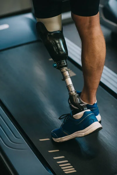 Обрезанный снимок спортсмена с искусственной ногой, идущего по беговой дорожке в спортзале — стоковое фото